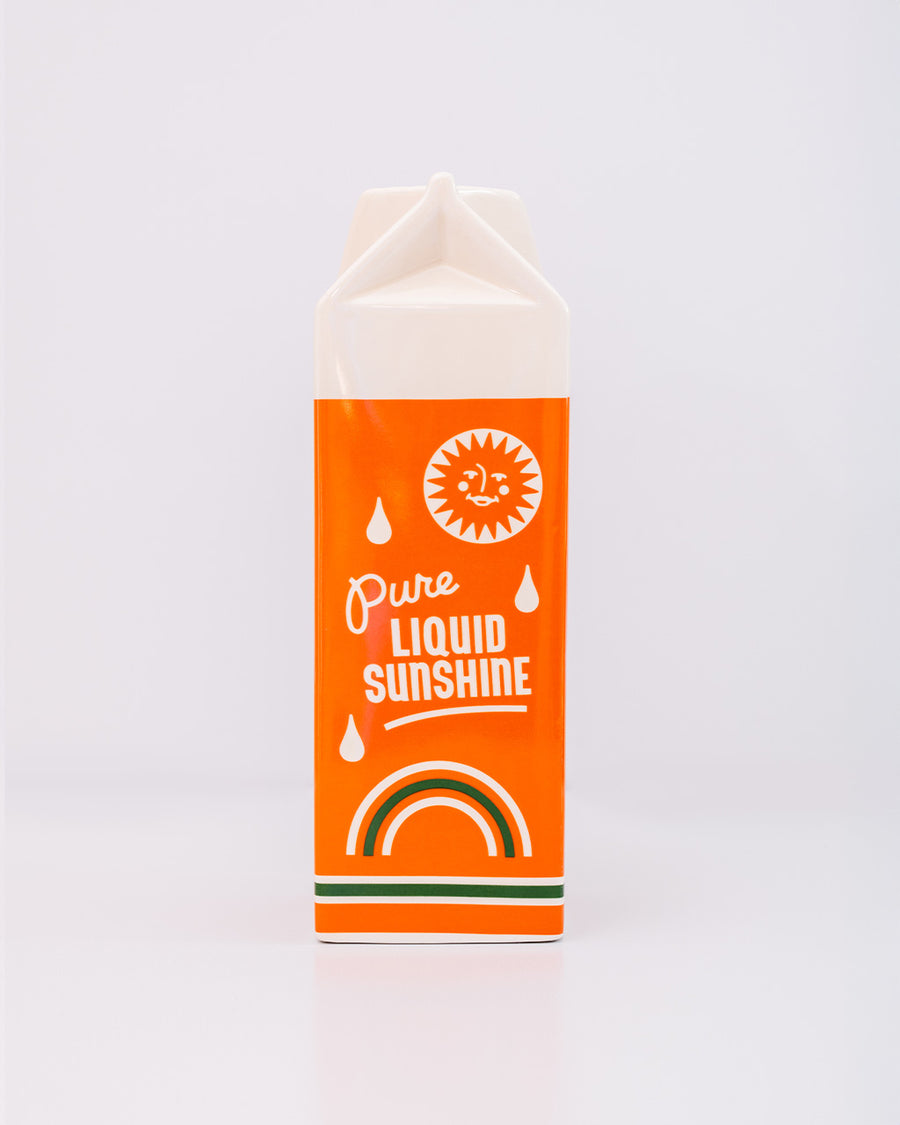 back view of ceramic orange juice carton-shaped vase that says 'pure liquid sunshine