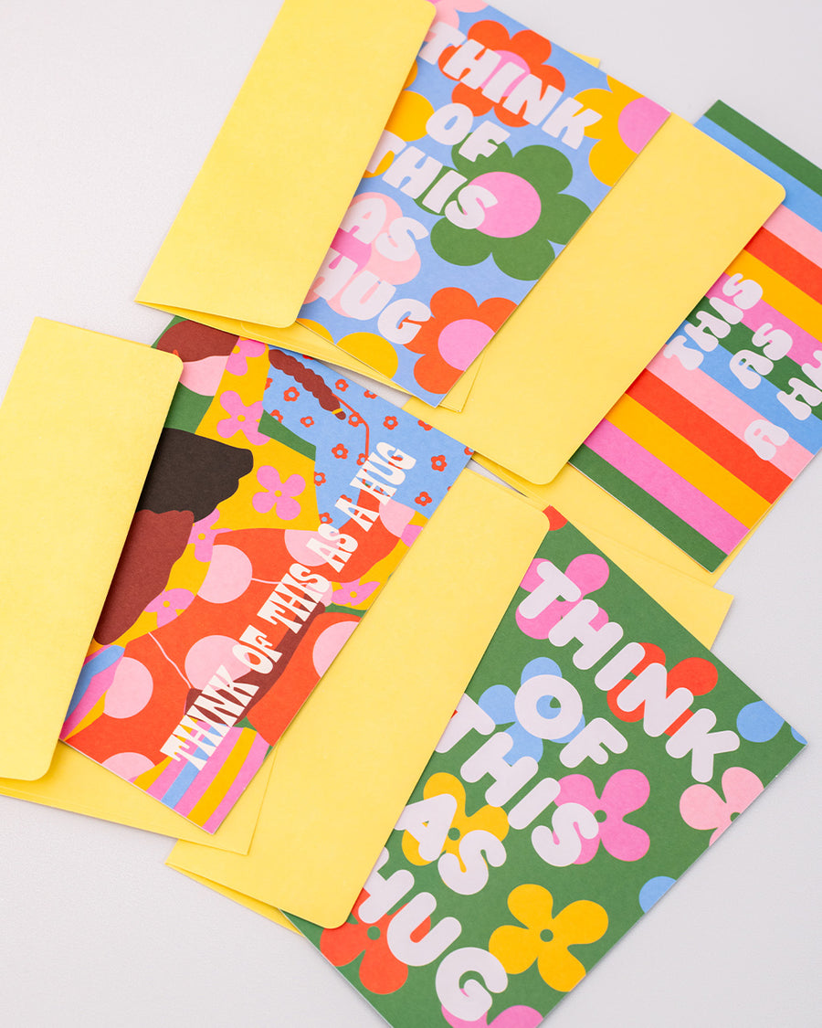 up close of set of 20 greeting cards with 4 styles of 'think of this as a hug' and pale yellow envelopes