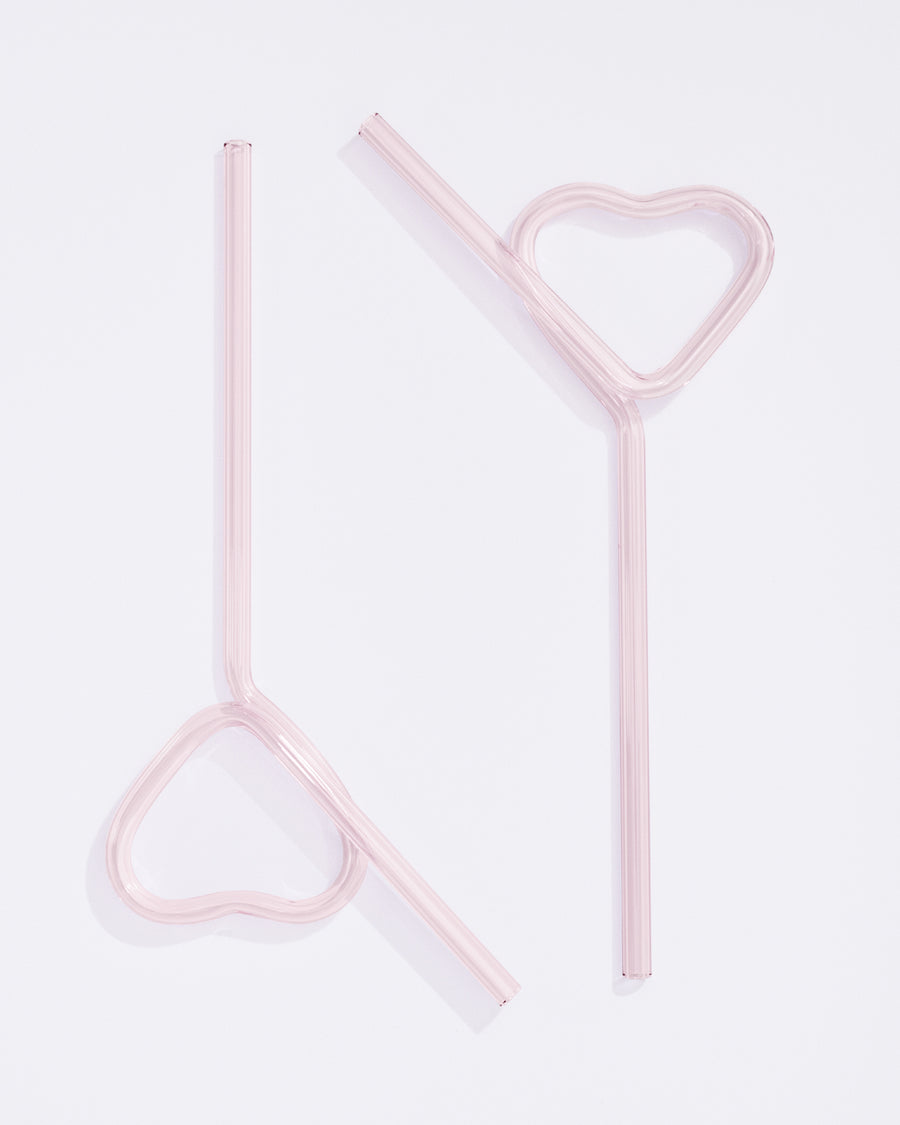 two light pink glass straws bent in the shape of hearts at the ends