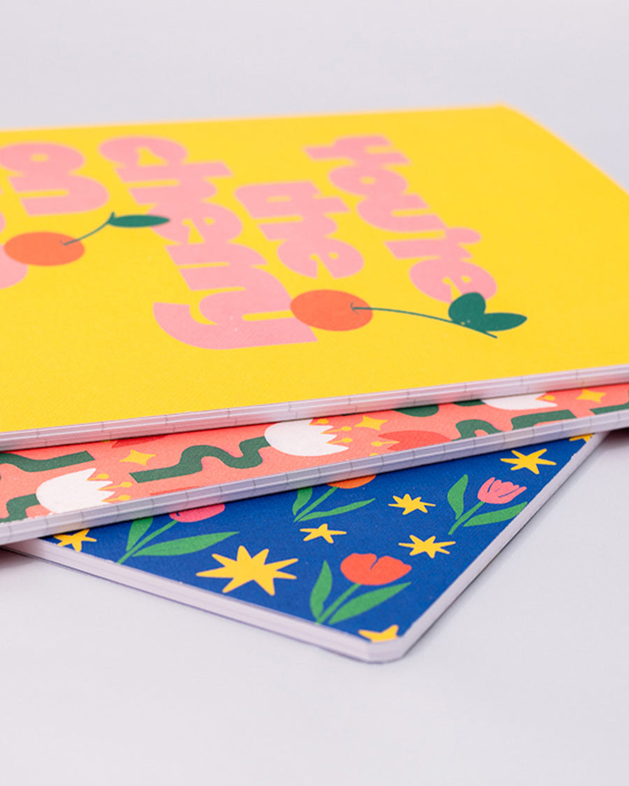 set of three notebook set: dark blue with tulip print, yellow with 'you're the cherry on top' typography, and pink mid century tulips stacked to show thickness