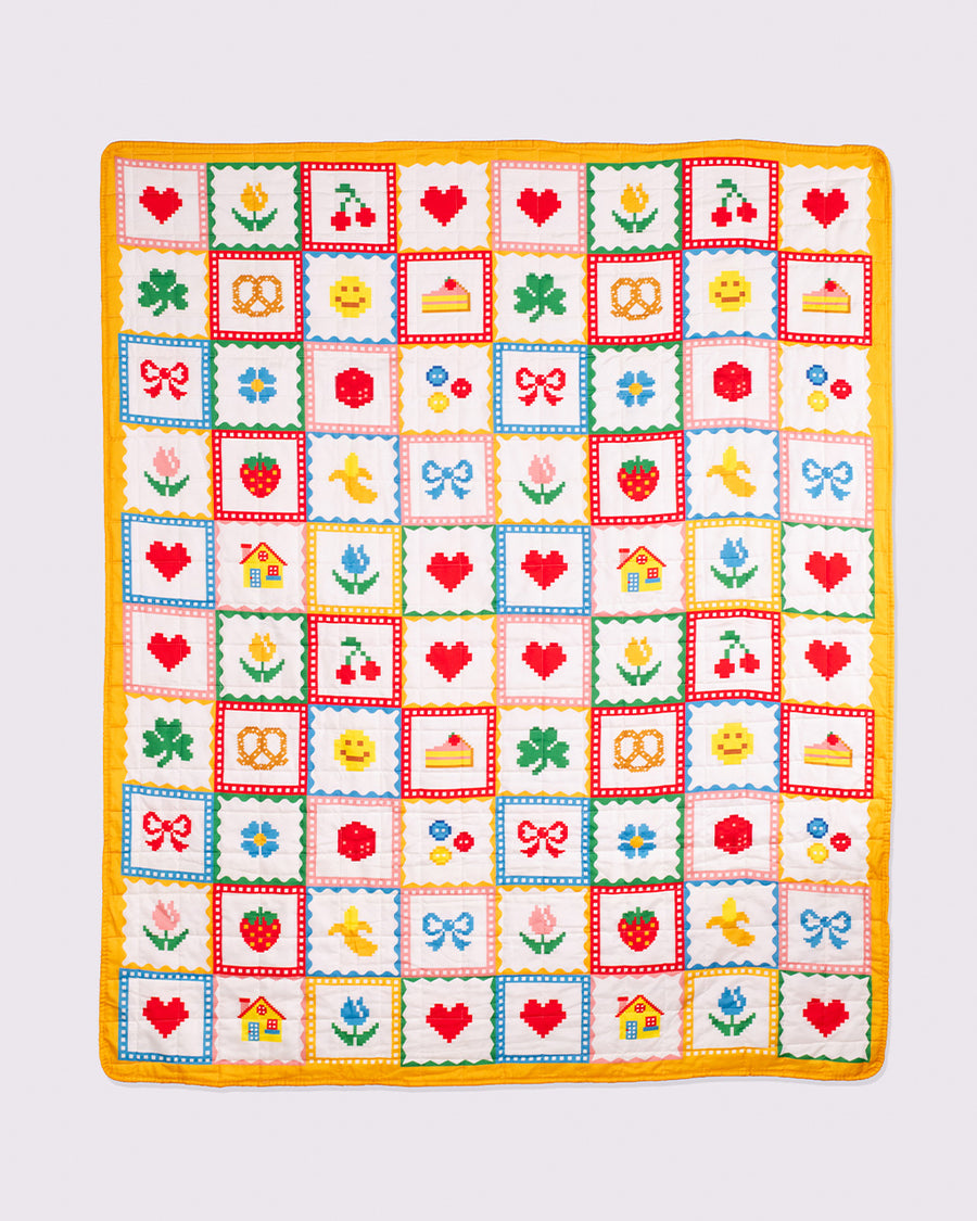 unfolded colorful patchwork quilted blanket with heart, shamrocks, pretzels, smiley faces, cakes, and bows