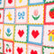 up close of colorful patchwork quilted blanket with heart, shamrocks, pretzels, smiley faces, cakes, and bows