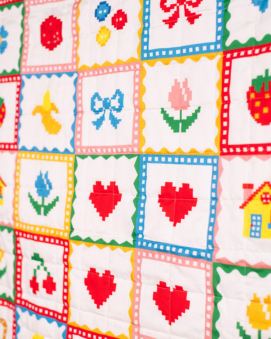 up close of colorful patchwork quilted blanket with heart, shamrocks, pretzels, smiley faces, cakes, and bows