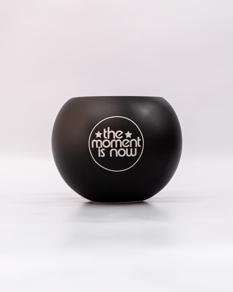 back view of black magic 8 ball shaped vase  that says 'the moment is now'