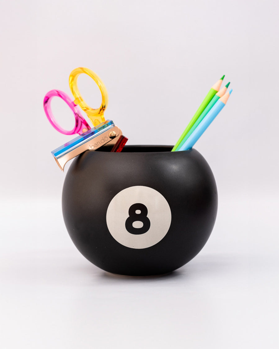 black magic 8 ball shaped vase with desk accessories inside