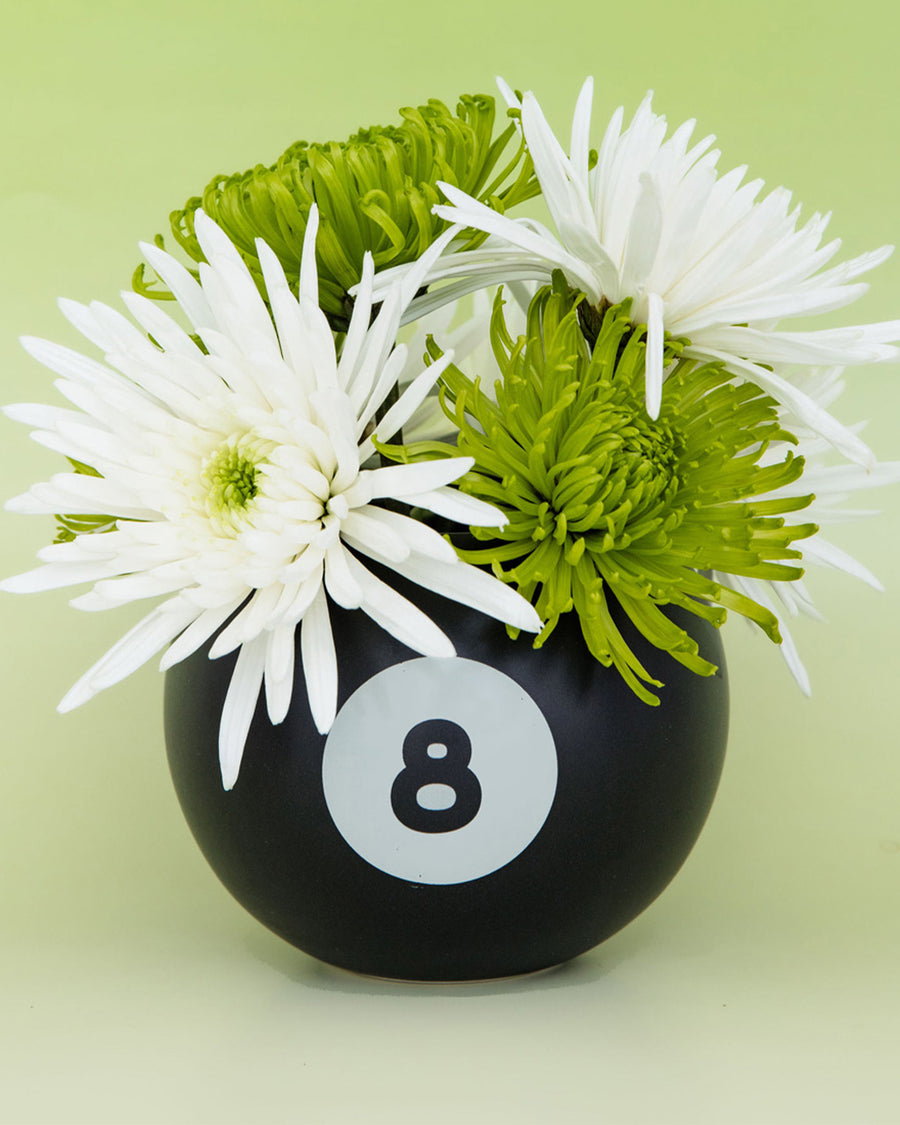 black magic 8 ball shaped vase with flowers inside