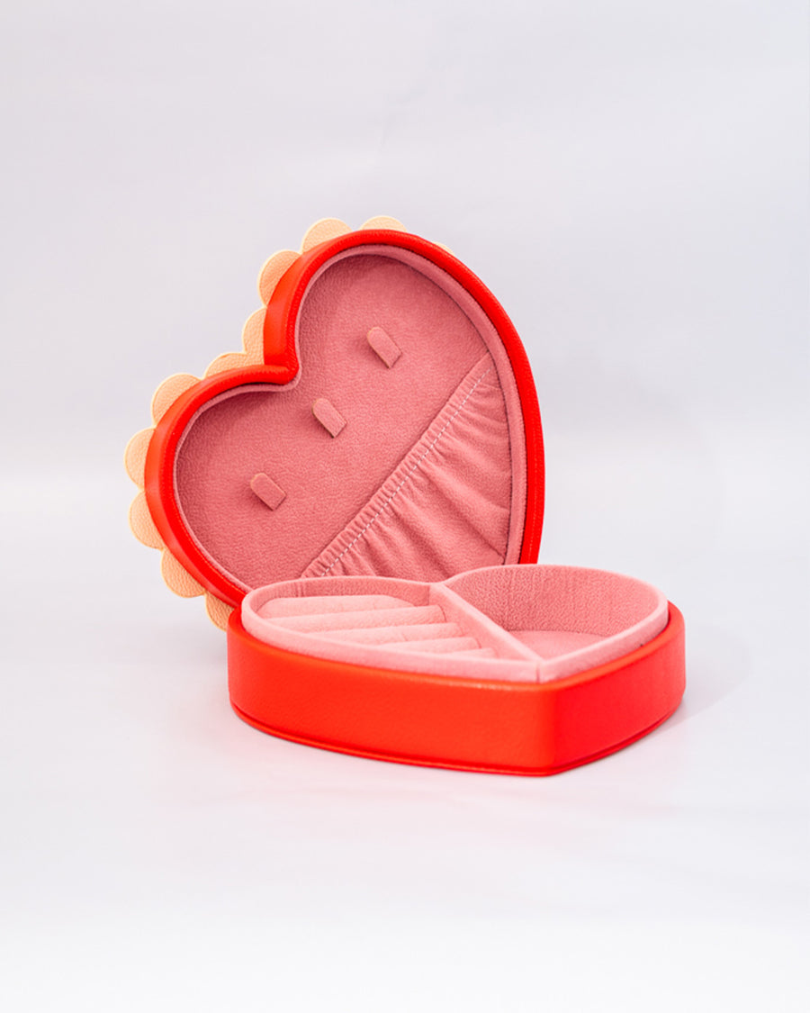 side view of red heart shaped jewelry box with pink interior and cream scalloped detail with 'sweet little jewelry' across the front