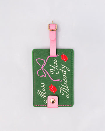 green luggage tag with pink strap and trim with 'miss you already' in cursive