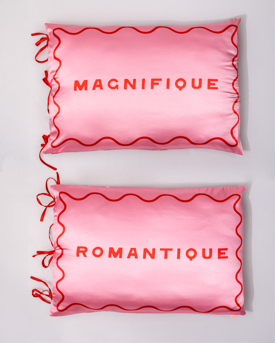 set of 2 pink pillowcases with red 'magnifique' and 'romantique' with red side tie closure and red squiggle border