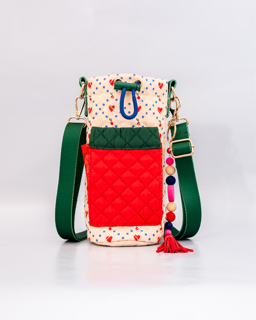 cream quilted water bottle sling with red and green front pouch, green adjustable strap and colorful beaded tassel keychain