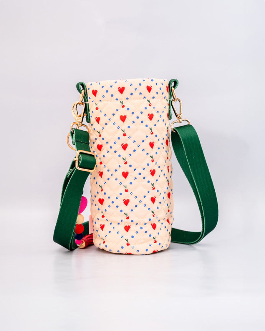 back view of cream quilted water bottle sling with red and green front pouch, green adjustable strap and colorful beaded tassel keychain