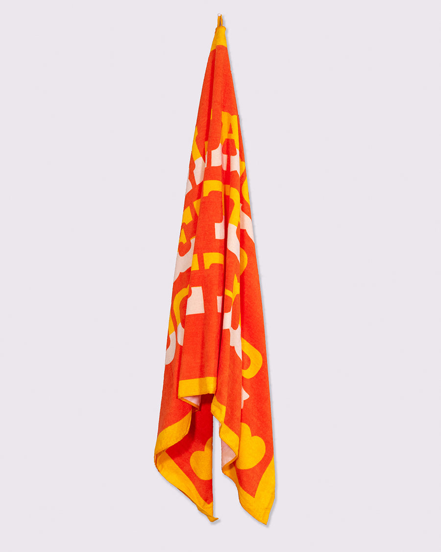 red oversized towel with golden yellow trim and yellow and white ombre 'always better together' hanging on a hook