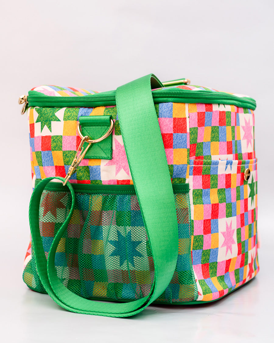 side view of colorful 'quilted' star lunch bag with green trim and strap and front pocket and green mesh side pocket