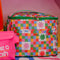 colorful 'quilted' star lunch bag with green trim and strap and front pocket next to pink waterproof bag