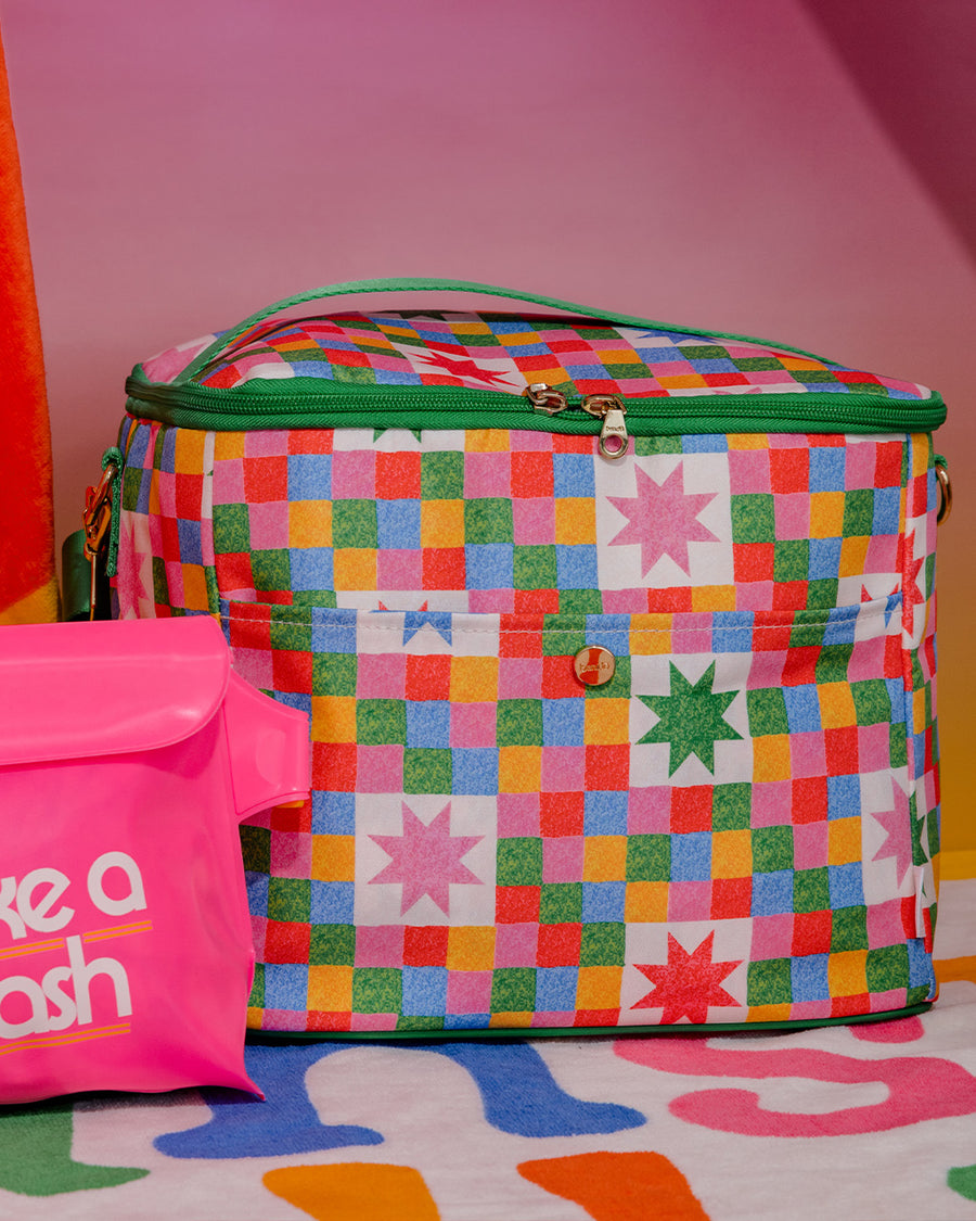 colorful 'quilted' star lunch bag with green trim and strap and front pocket next to pink waterproof bag