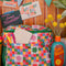 colorful 'quilted' star lunch bag with green trim and strap and front pocket and sunblock vase next to it