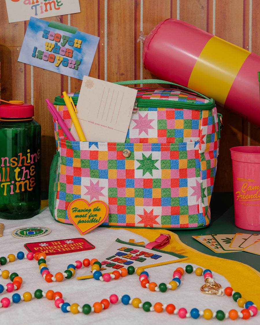 colorful beaded crossbody phone lanyard with gold carabiners on a table surrounded by colorful items