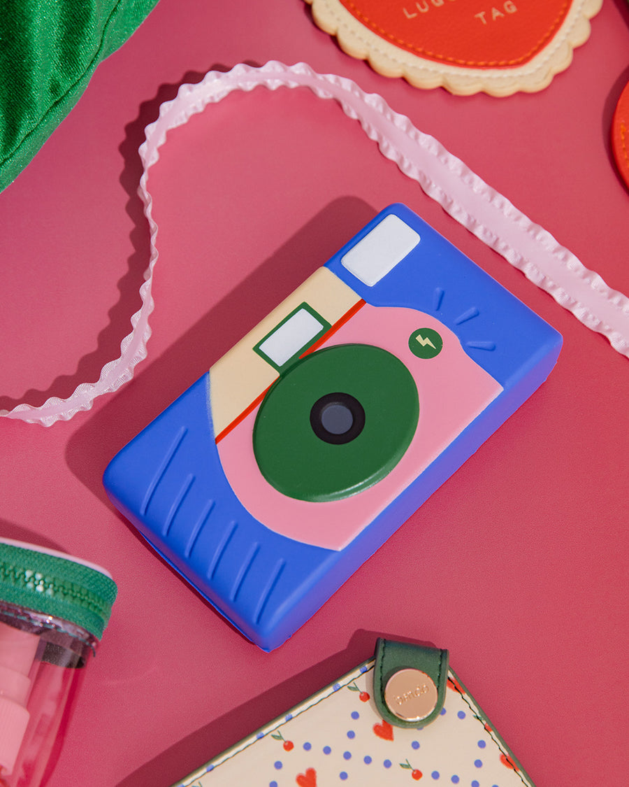 blue, pink, green and cream camera de-stress ball on a pink ground