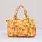 orange quilted duffel bag with handles and adjustable strap and has an all over yellow, white, and green retro floral print