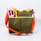 army green canvas gardening tool bag with red strap and yellow scalloped top edge with garden tools inside