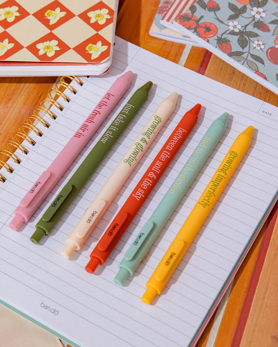 set of 6 colorful clickable pen set with various gardening sayings on a notebook