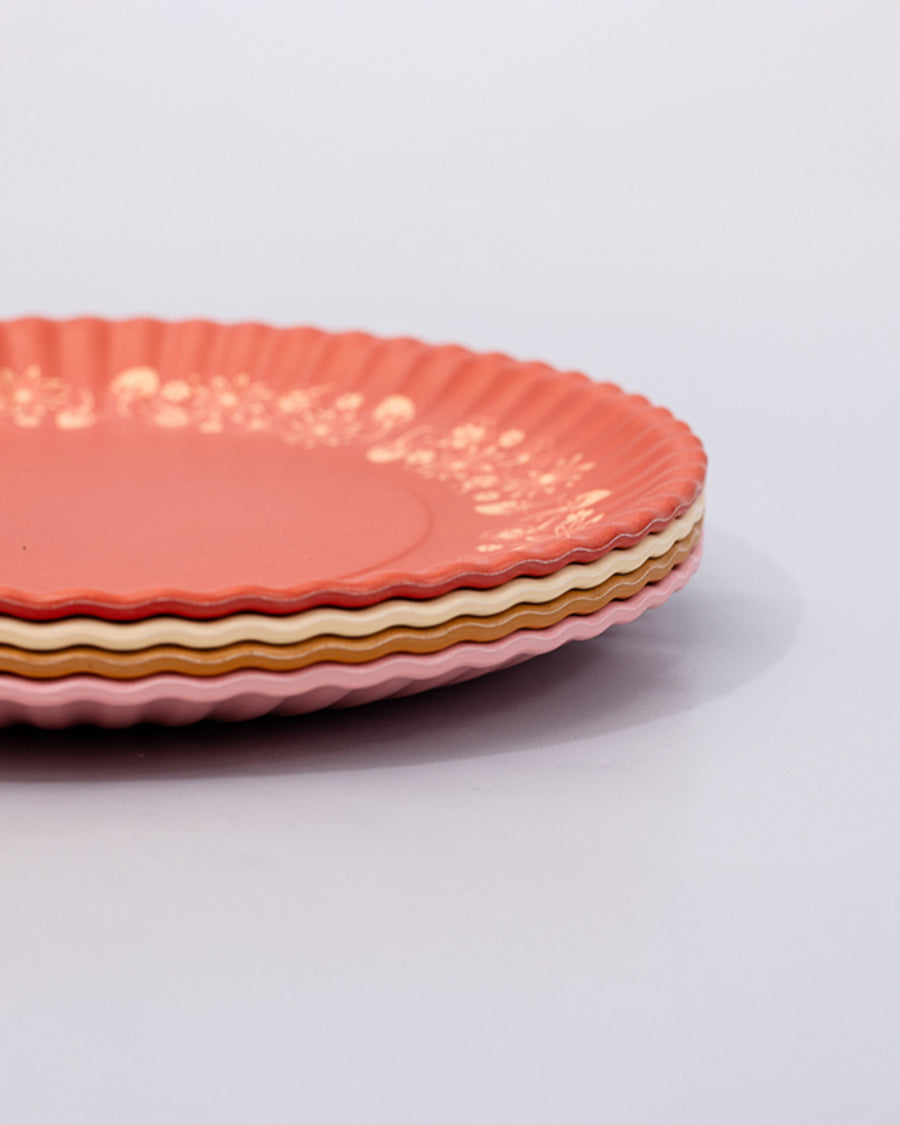 side view of set of 4 dessert plates with ridge edges: golden strawberry, pink with green garden border, cream with green plant print and red checkered border and red with golden garden border stacked on each other