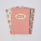 fanned out set of 3 pocket notebooks: red vertical stripes with cream circle that says 'growing imperfectly', blue and cream diamond with fruit print, and light blue strawberry and tomato print