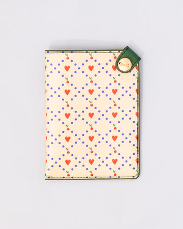 cream passport holder with blue diamond design with hearts and cherries and green side snap closure