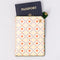 cream passport holder with blue diamond design with hearts and cherries and green side snap closure with a passport sticking out