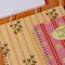 pale yellow large notebook with white floral and strawberry print and dark yellow vertical stripes on a table