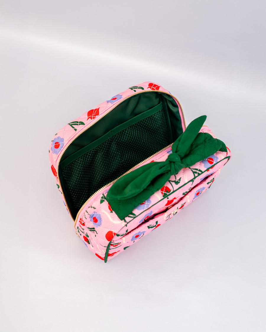 green interior of pink quilted toiletry bag with green bow handle and all over periwinkle flower, cherries, bow and lip print