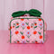 pink quilted toiletry bag with green bow handle and all over periwinkle flower, cherries, bow and lip print on a pink counter and light pink backdrop