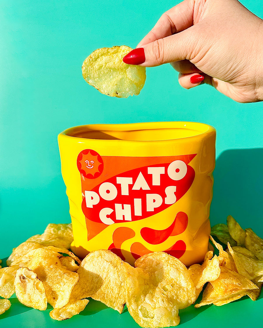 model pulling potato chip out of yellow potato chips shaped vase