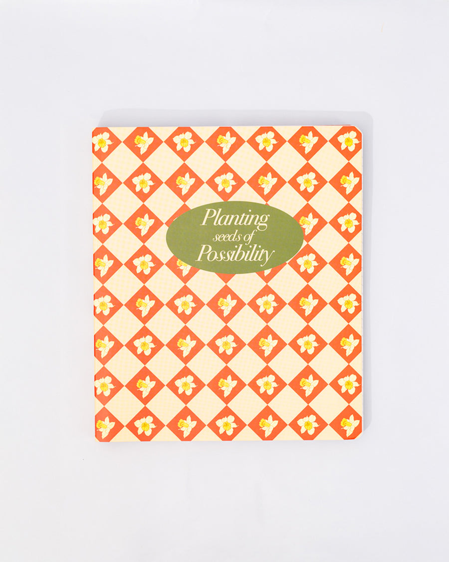 cream waterproof notebook with red diamond and daffodil print with green 'planting seeds of possibility'