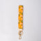 orange wristlet lanyard with white, yellow and green retro floral print and gold hardware