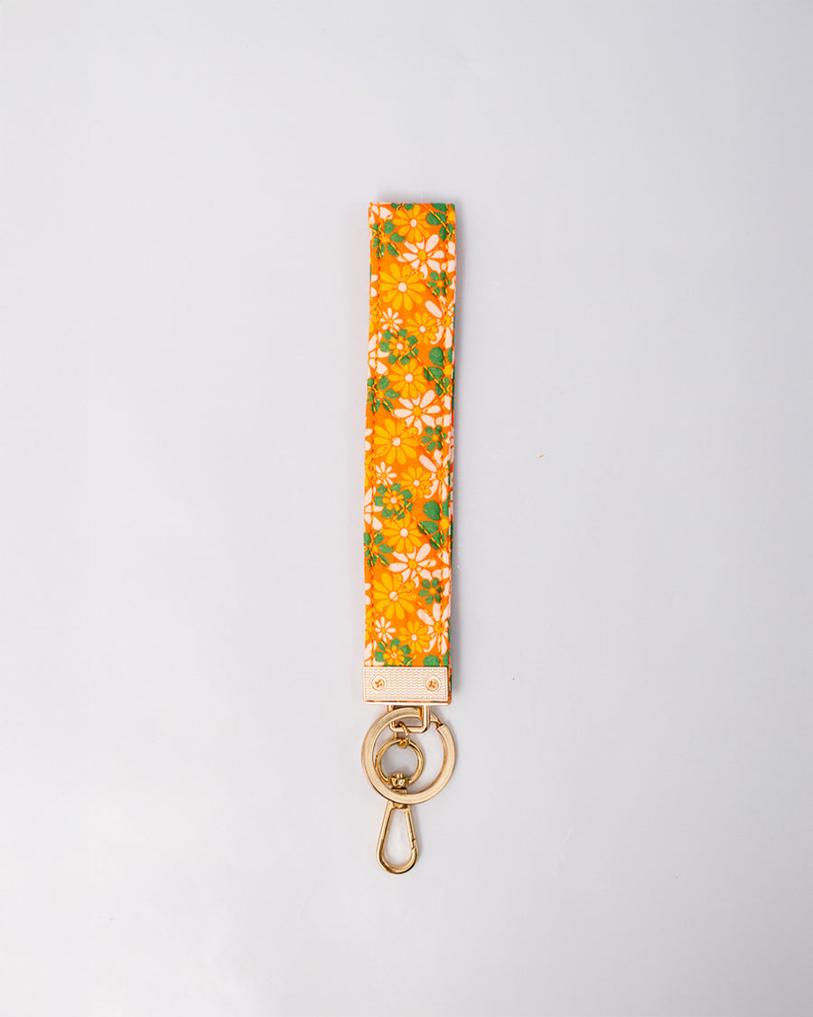 orange wristlet lanyard with white, yellow and green retro floral print and gold hardware