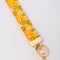 up close of orange wristlet lanyard with white, yellow and green retro floral print and gold hardware