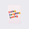 white notebook that says Living Laughing Loving in bold, colorful letters