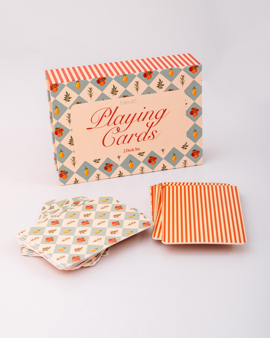 packaged set of two playing card decks with cream and red stripes and blue diamond fruit print with decks next to packaging