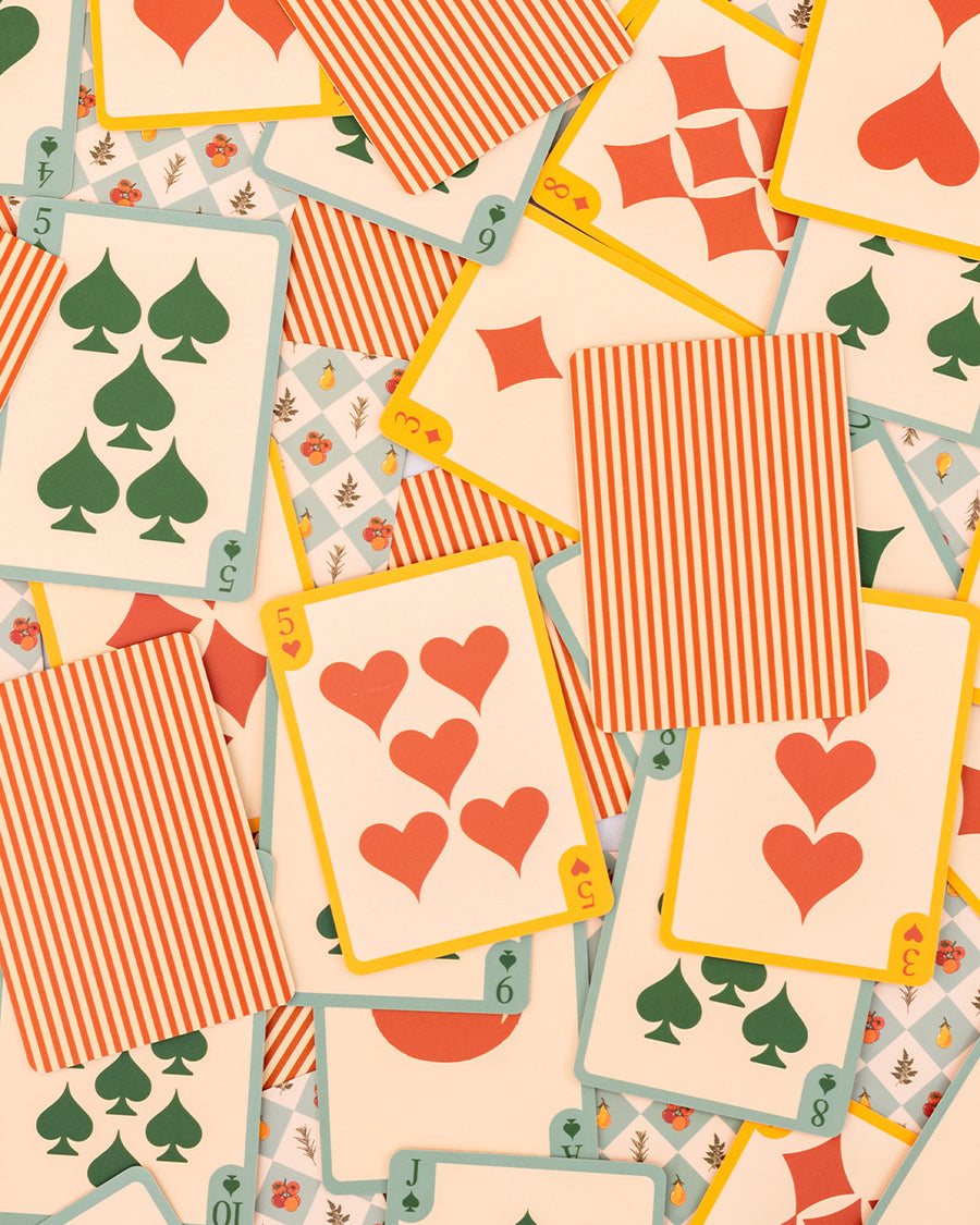 scattered two playing card decks with cream and red stripes and blue diamond fruit print