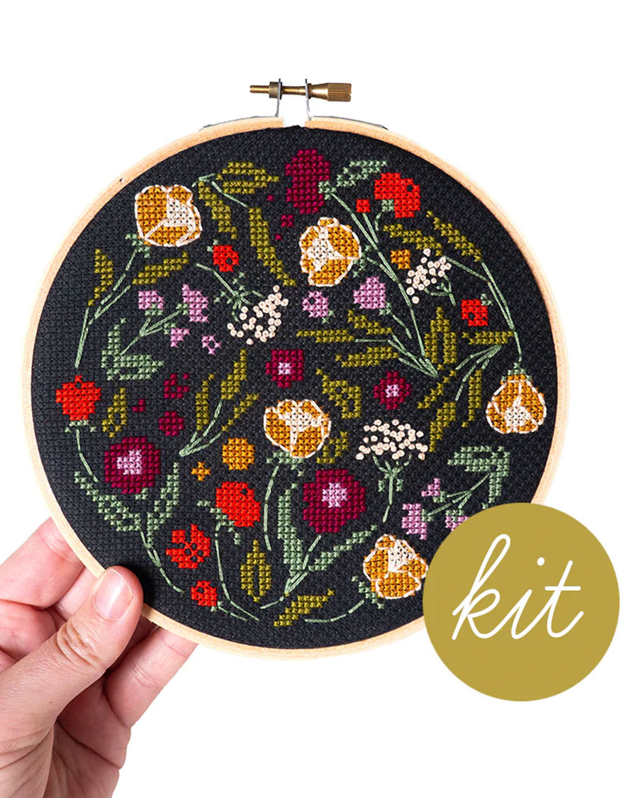 model holding black embroidered cross stitch kit with colorful floral print