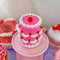 top view of hot pink 'tiered' birthday cake jar with tight seal lid and white frosting and cherry decorations