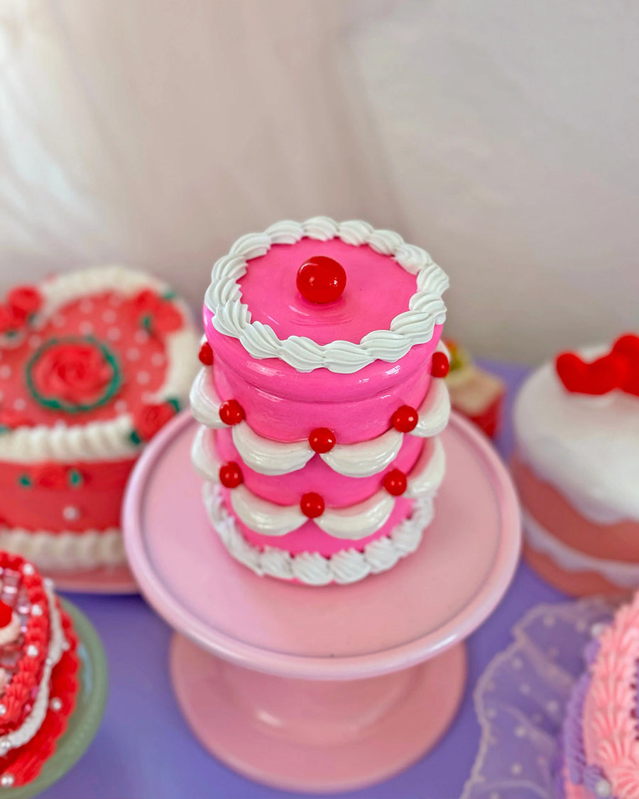 top view of hot pink 'tiered' birthday cake jar with tight seal lid and white frosting and cherry decorations