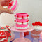 model pulling lid off of hot pink 'tiered' birthday cake jar with white frosting and cherry decorations