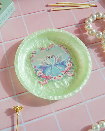 green tray with two swans in a pond with a floral heart border surrounding them