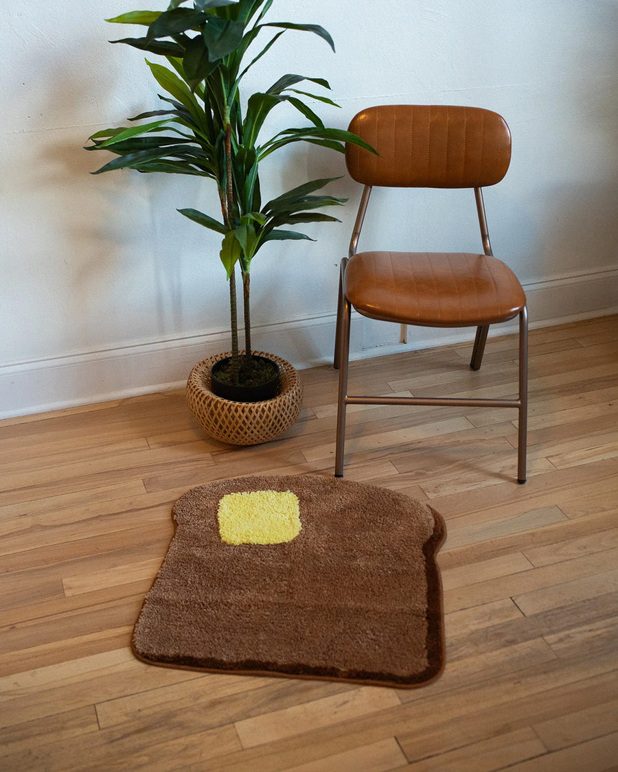 toast and butter shaped throw rug on the floor with chair and plant