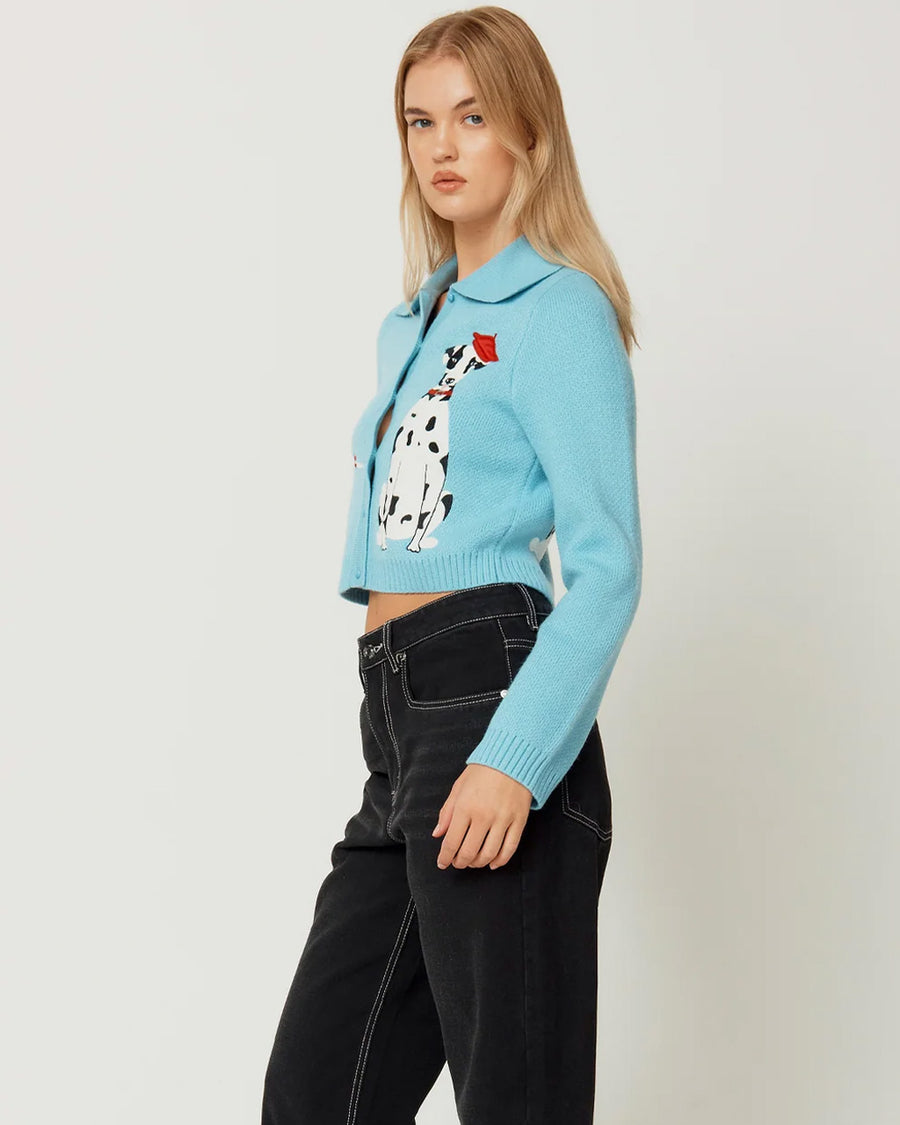 side view of model wearing light blue cropped cardigan with Dalmatian wearing a red beret design wrapping across the side and back