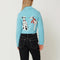 back view of model wearing light blue cropped cardigan with Dalmatian wearing a red beret design wrapping across the side and back