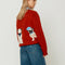 back view of model wearing red oversized crew sweater with pug wearing a blue beret on the back