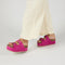 model wearing platform suede slide sandals with thick straps and metal buckle closures in fuschia